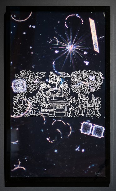 A dark background filled with stars and celestial patterns, featuring a central white illustration depicting a group of people gathered around a table, surrounded by stylized trees and motifs. The overall composition evokes a sense of community and cosmic wonder.