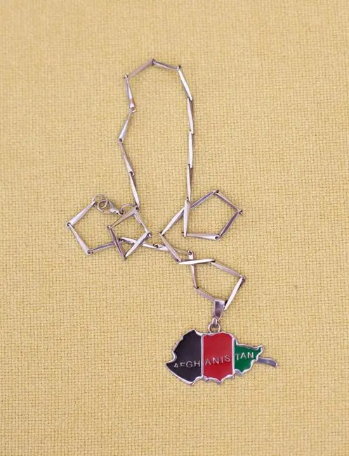 Eine silberne Kette mit einem Anhänger in Form von Afghanistan, der in den Farben Schwarz, Rot und Grün gehalten ist. Der Anhänger trägt das Wort „AFGHANISTAN“. Der Hintergrund ist gelb.