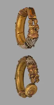 Golden ornamental bangle featuring intricate sculptures of two figures. The bangle is adorned with detailed patterns and gemstones, showcasing a mix of elegance and craftsmanship from a particular cultural heritage. The design is visible from multiple angles to highlight its artistic features.