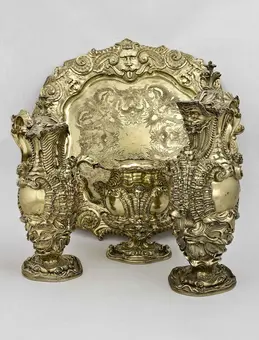 A decorative silver set featuring an ornate tray and three intricately designed vases with elaborate patterns. The pieces exhibit a vintage style and are embellished with detailed motifs, reflecting craftsmanship and elegance. The background is plain to emphasize the objects.