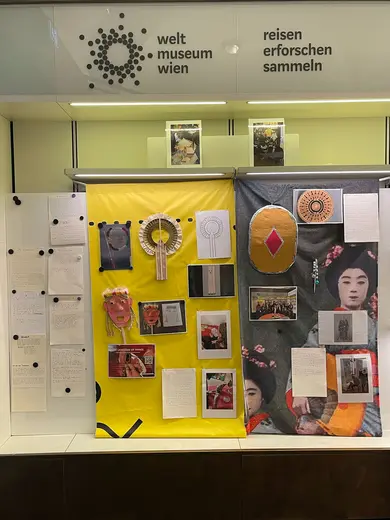 Display at the Weltmuseum Wien featuring a colorful exhibit. The left side has yellow fabric with images, texts, and decorative items. The right side showcases gray fabric with various photographs and written content, all highlighting cultural themes and artistic expressions.