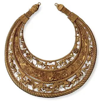 An ornate gold necklace with three layered hoops. The top and bottom layers are twisted, while the middle layer features intricate cut-out designs depicting animals and figures, surrounded by floral motifs. The necklace has decorative ends shaped like animal heads.