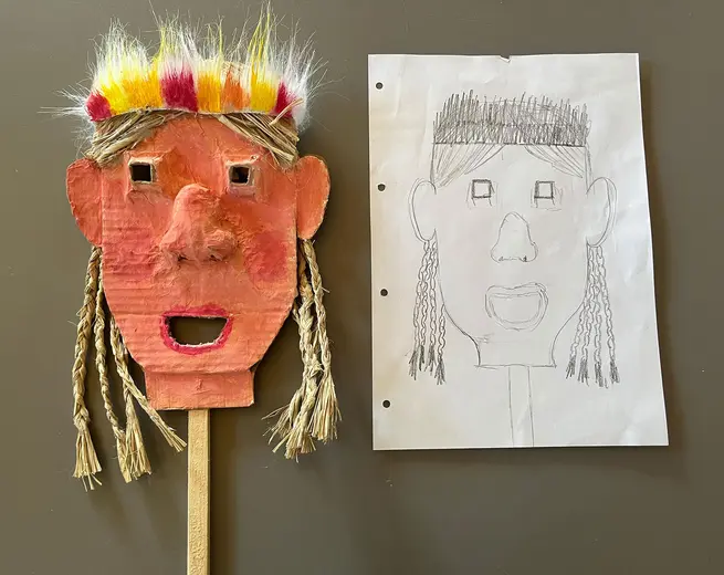 A colorful handmade mask with braided straw hair and a bright headdress is displayed on the left, while on the right is a sketch of a similar face, featuring simple facial features and straight hair. Both are expressive and playful in style.