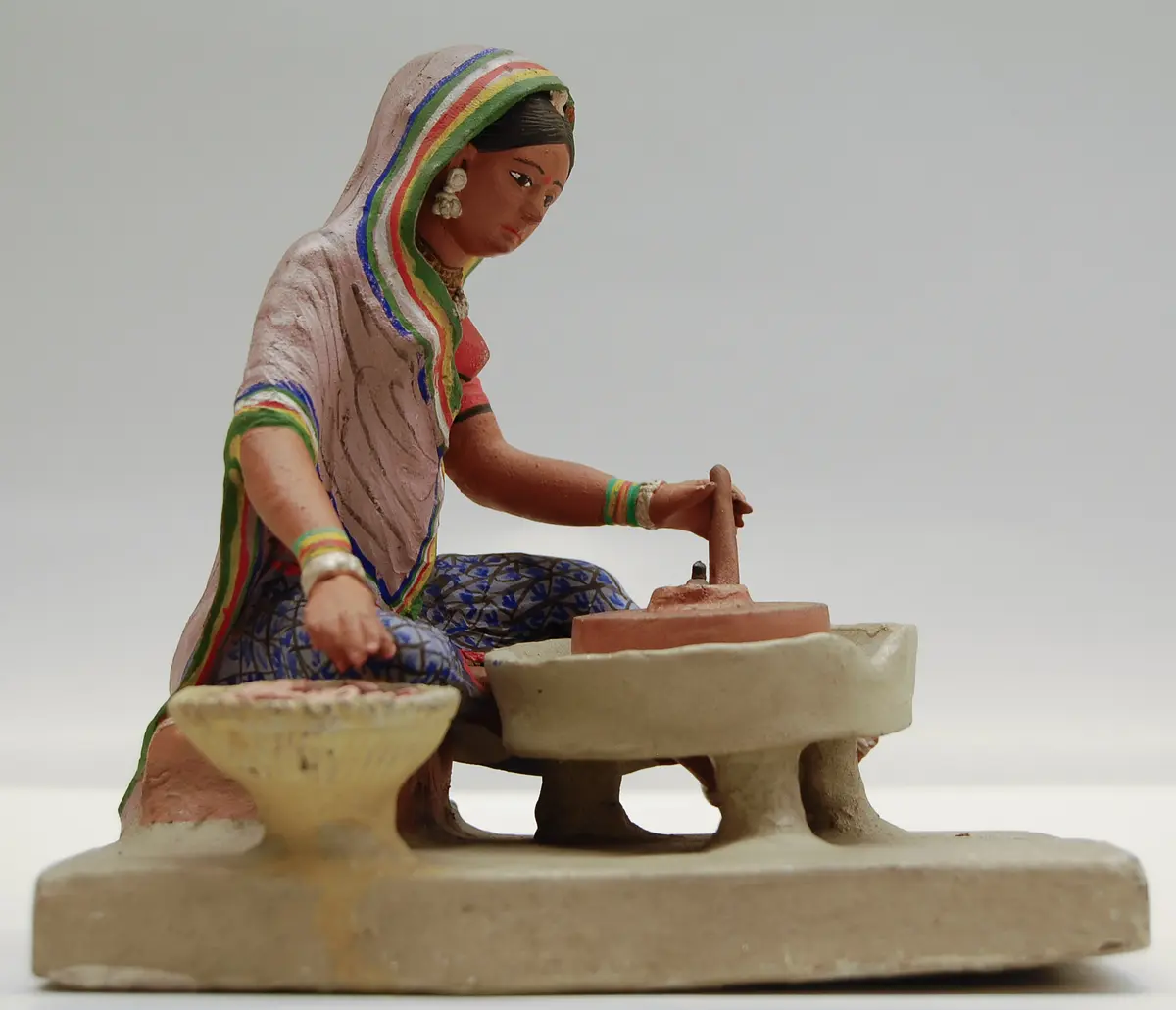 Frau beim Mahlen mit der Handmühle