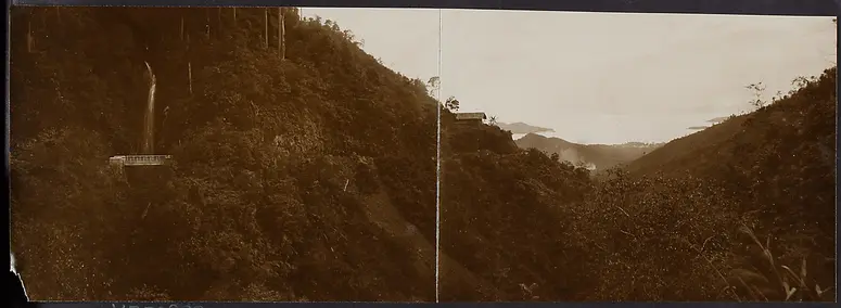 Panorama: bewaldete Schlucht mit kleinem Wasserfall; im Hintergrund Meeresbucht