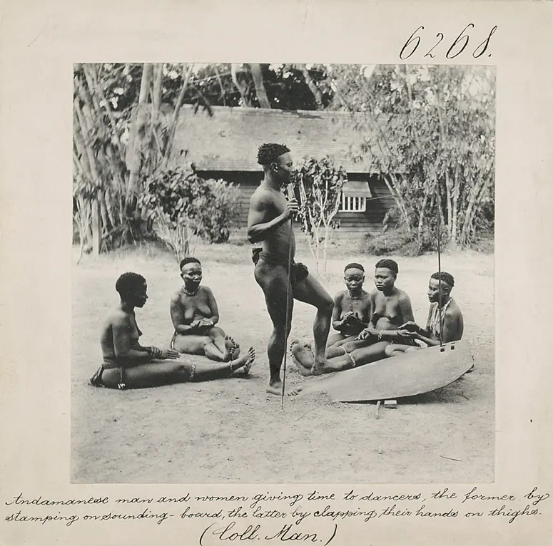 Andamanese man and women giving time to dancers, the former by stamping on sounding-board, the latter by clapping their hands on thighs