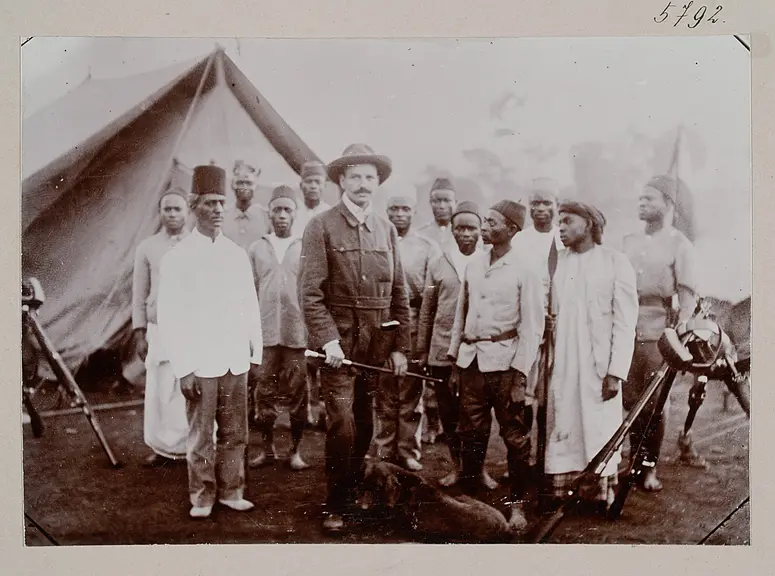 Dr. M. Schöller mit seinen Gewehrträgern und Boys sowie Ober-Muniampara Msimba (Moschi)